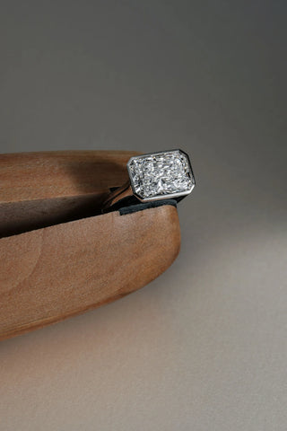 Platinum bezel-set ring featuring a 5.08ct long radiant lab-grown diamond, D colour, VVS2 clarity held in wooden ring clamp.