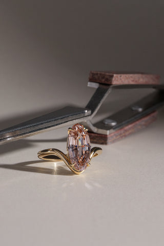 Madison 18k yellow gold engagement ring with a 3.15ct light brown oval step cut lab-grown diamond on a contoured band, resting beneath jeweller's tools