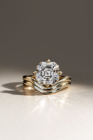 Nikola custom engagement ring with an Asscher-cut diamond in eight pyramid claws on a contoured yellow gold band, shown with a matching curved wedding band