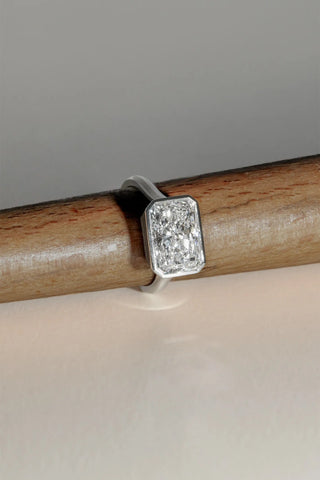 Platinum bezel-set ring featuring a 5.08ct long radiant lab-grown diamond, D colour, VVS2 clarity on wooden ring sizer.